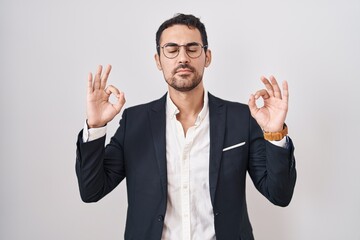 Handsome business hispanic man standing over white background relaxed and smiling with eyes closed doing meditation gesture with fingers. yoga concept.