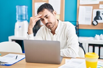 Young hispanic man business worker stressed using laptop at office