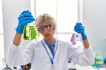 Young blond man scientist holding test tubes at laboratory
