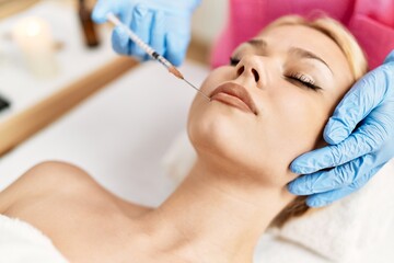 Obraz na płótnie Canvas Young caucasian woman lying on table having antiaging treatment at beauty salon