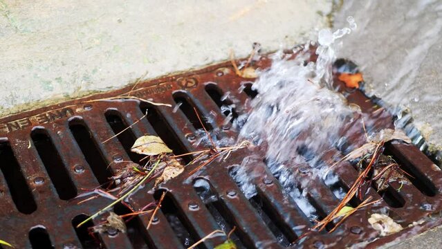 the flow of water after heavy rain flows into the sewer through the metal grate of the storm collector. rain sewer system of the city