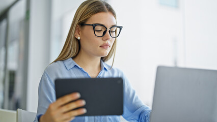 Young blonde woman business worker using laptop and touchpad at office