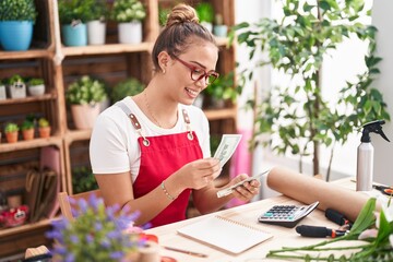 Young beautiful hispanic woman florist smiling confident counting dollars at florist