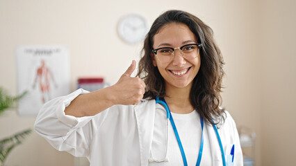 Young beautiful hispanic woman doctor doing thumb up at clinic