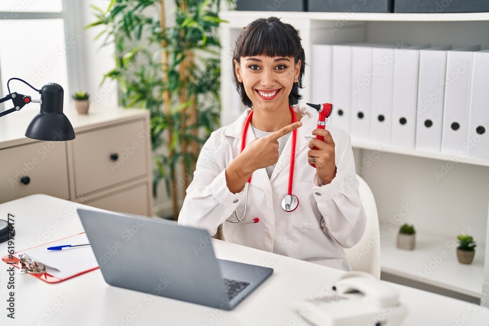 Poster young hispanic doctor woman holding ear thermometer smiling happy pointing with hand and finger