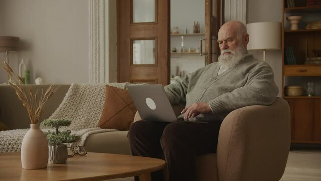 Confused Elderly Man Reading a Message on Laptop
