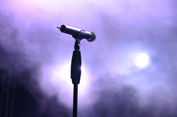 Microphone on the stage. Vocal mic with fog and lights in background. Concert. 