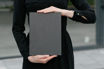 Black book cover in woman's hands. Book cover for mock up