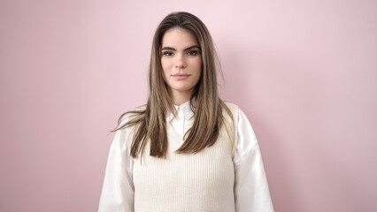 Fototapeta premium Young beautiful hispanic woman standing with serious expression over isolated pink background