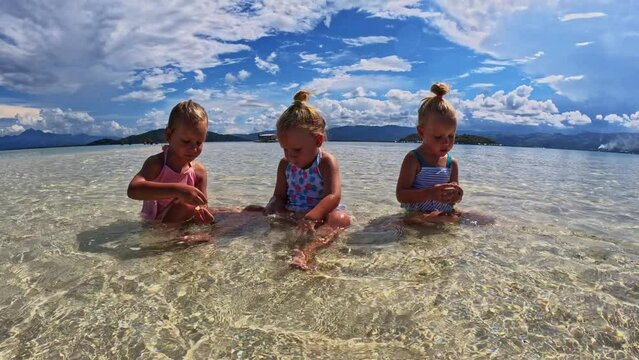 Children of the Triplet Sister play on the beach and in shallow water