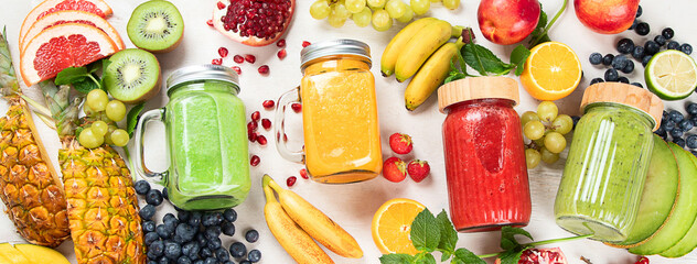 Fresh fruit and vegetable smoothies or juice  with various ingredients on light background.