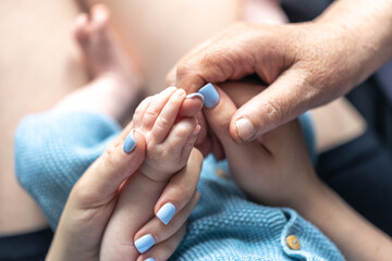 Close-up, the hands of the baby, mom and grandmother.