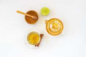 Top view of a cup of tea with ginger root, lime, cinnamon and teapot on white background. Health drink concept..