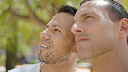 Two men couple looking to the sky with relaxed expression at park