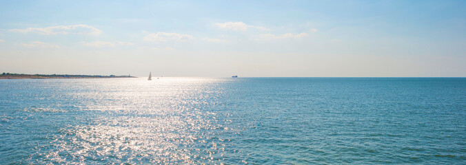 Sand beach along a sea under a dark blue cloudy sky in bright sunlight in summer, Zeeland, the...