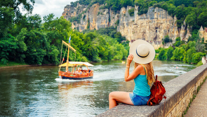 Woman tourist looking at canoe and boat in Dordogne river- activity, adventure, travel destination-...