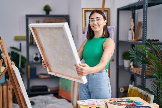 Young hispanic woman artist smiling confident holding draw at art studio