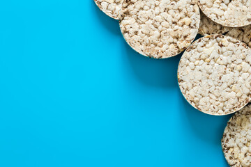 Puffed rice cakes on blue background, flat lay, copy space.
