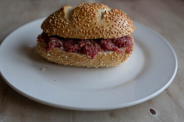 Bun with fresh and lean ground beef, pepper and salt seasoning on a plate