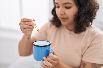 Young woman pouring medication on coffee at home