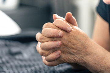 The hands of an elderly woman folded in prayer.