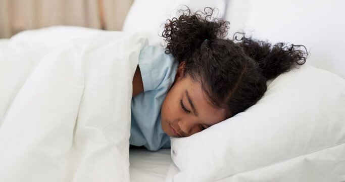 Tired, relax and child sleeping in her bed for rest and dreaming in the morning on a weekend. Exhausted, cute and young girl kid taking a nap in her bedroom in the modern family home or house.