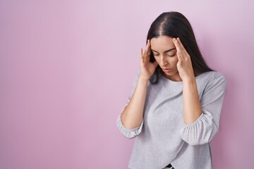 Young brunette woman standing over pink background with sad expression covering face with hands while crying. depression concept.