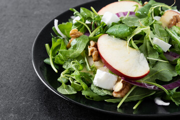Autumn salad with apples and walnuts on black slate background. Close up