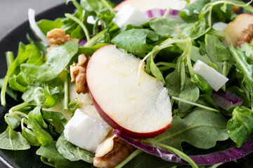 Autumn salad with apples and walnuts on black slate background. Close up