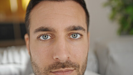 Young hispanic man sitting on sofa with relaxed expression at home