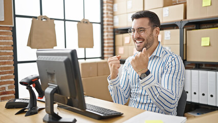 Young hispanic man ecommerce business worker using computer with winner expression at office