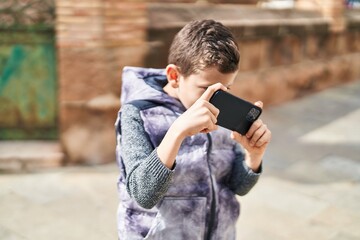 Blond child playing video game by the smartphone at street