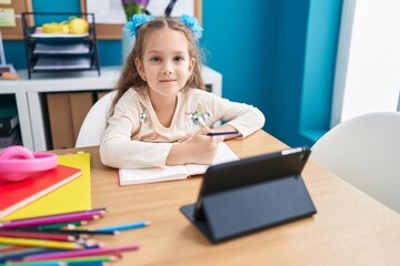 Fototapeta premium Adorable caucasian girl student using touchpad writing on notebook at office