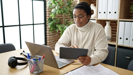 African american woman business worker using touchpad and laptop at office