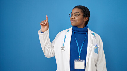 African american woman doctor smiling pointing to the side over isolated blue background