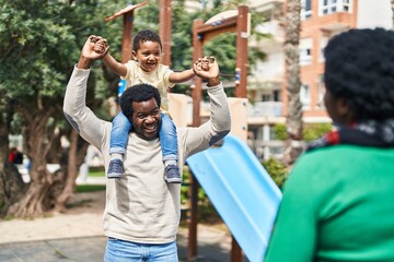African american family holding boy on shoulders at playground