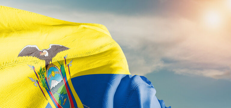 Ecuador national flag cloth fabric waving on beautiful sky Background.