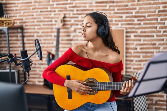 Young african american woman musician playing classical guitar at music studio