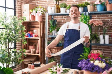 Young hispanic man florist smiling confident holding gift lace at florist