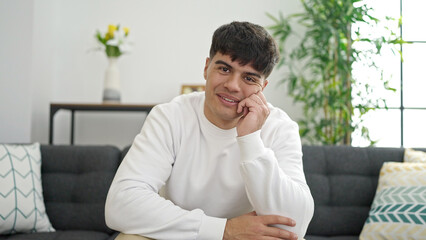 Young hispanic man smiling confident sitting on sofa at home