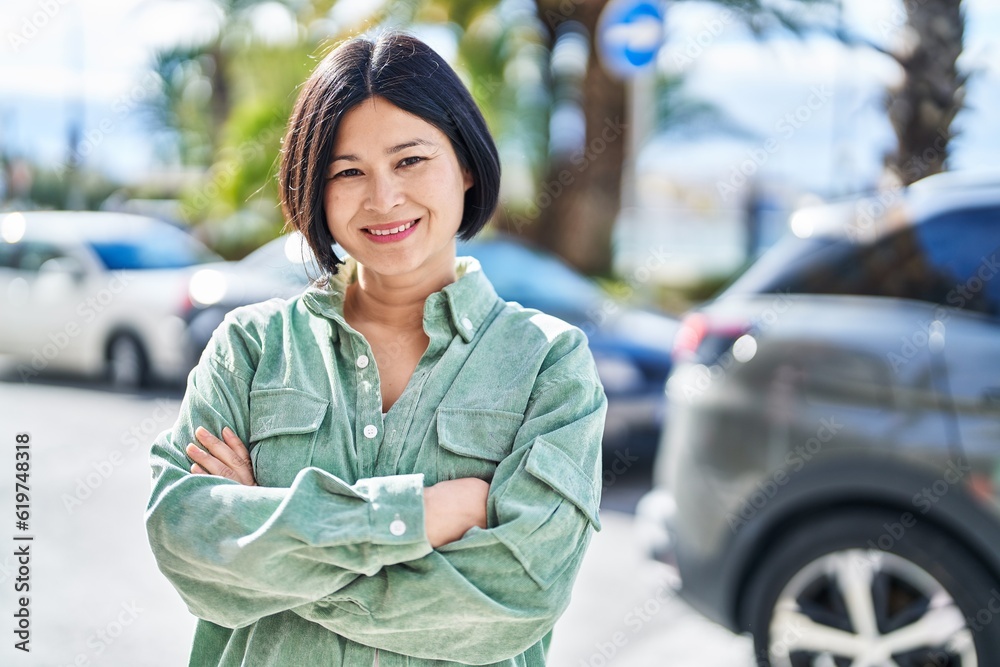 Sticker Young chinese woman smiling confident standing with arms crossed gesture at street