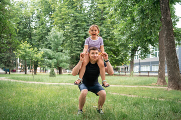 Fototapeta premium father doing squats with child daughter on the shoulders. active workout with family, healthy parenting 