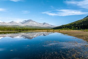 Fototapeta na wymiar Reflection of mountains on a calm lake in Rondane National Park, Norway