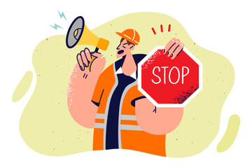 Man builder with stop sign shouts into megaphone warning people of danger due to road repair