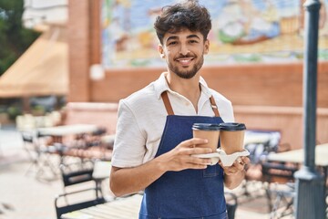Young arab man waiter smiling confident holding take away coffee at restaurant