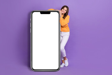 Full length photo of shiny girl dressed orange sweatshirt browsing instagram twitter empty space isolated purple color background