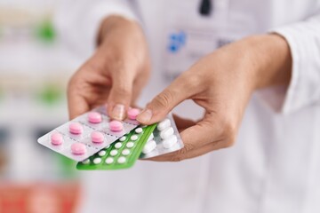 Young blonde woman pharmacist holding pills tablets at pharmacy