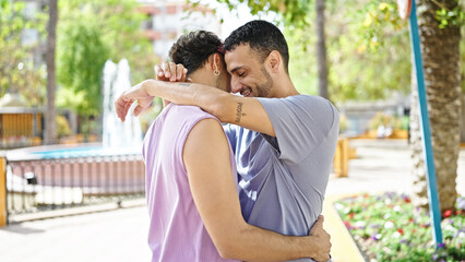 Fototapeta premium Two men couple smiling confident hugging each other at park