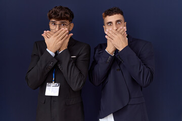 Two hispanic business men wearing business clothes shocked covering mouth with hands for mistake. secret concept.