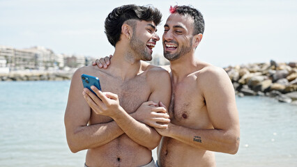 Two men tourist couple smiling confident using smartphone at beach